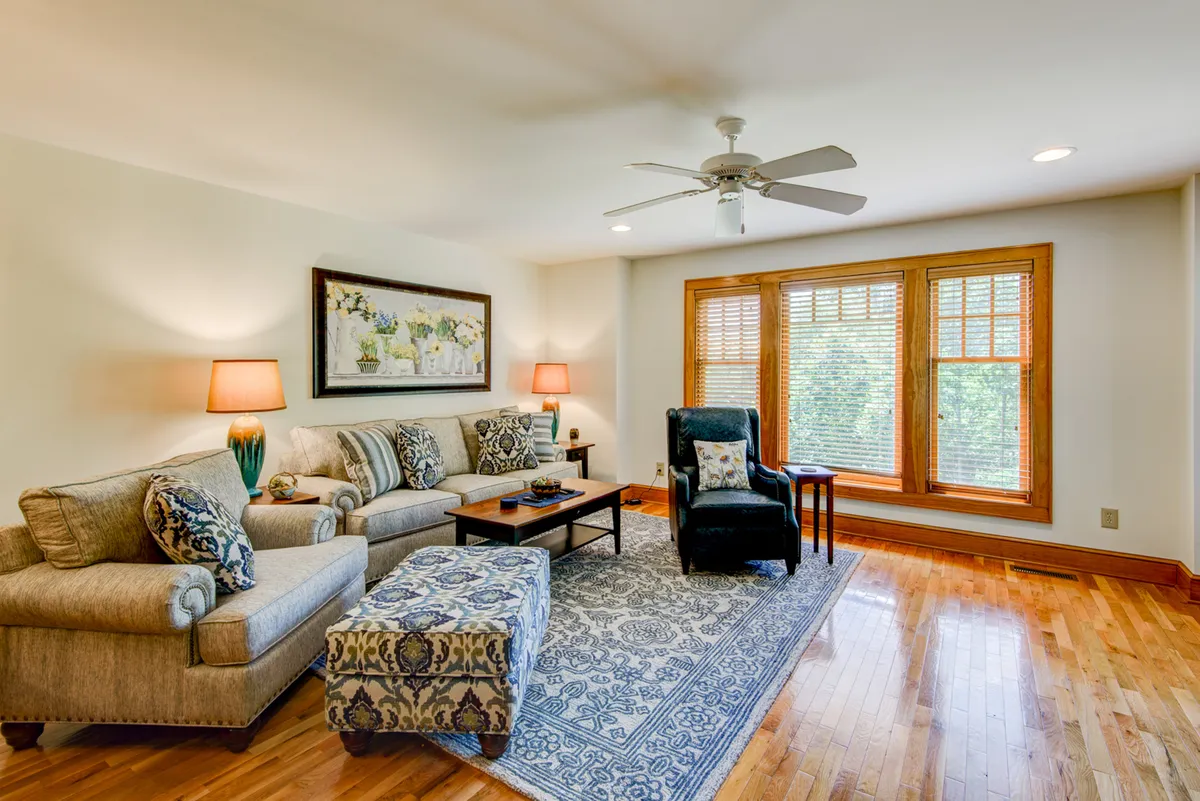 A comfortable living area with a sofa, coffee table, armchair, window, and rug. The space is designed for relaxation, reading, or quiet conversation, with soft lighting and inviting furnishings.