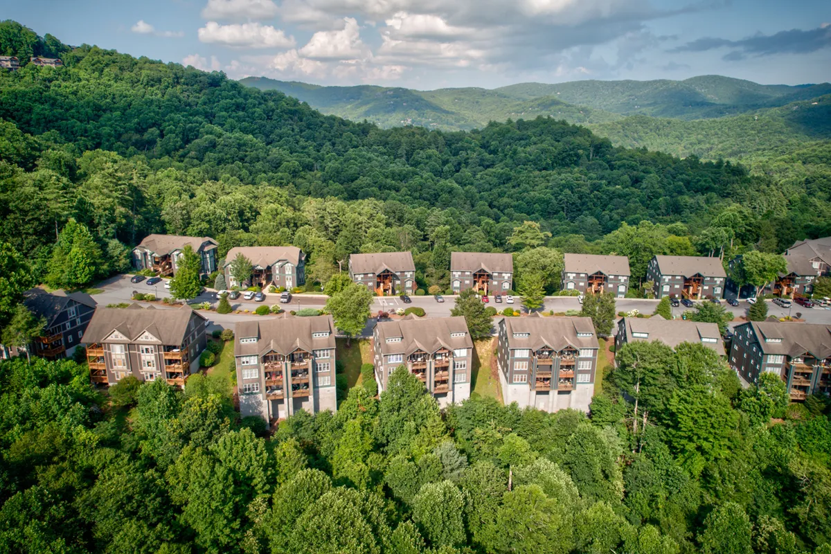 A sweeping view of the Echota community nestled in a lush, mountainous landscape, with residential buildings blending into the greenery. The backdrop of mountains and open skies highlights the site's natural beauty and sense of escape.