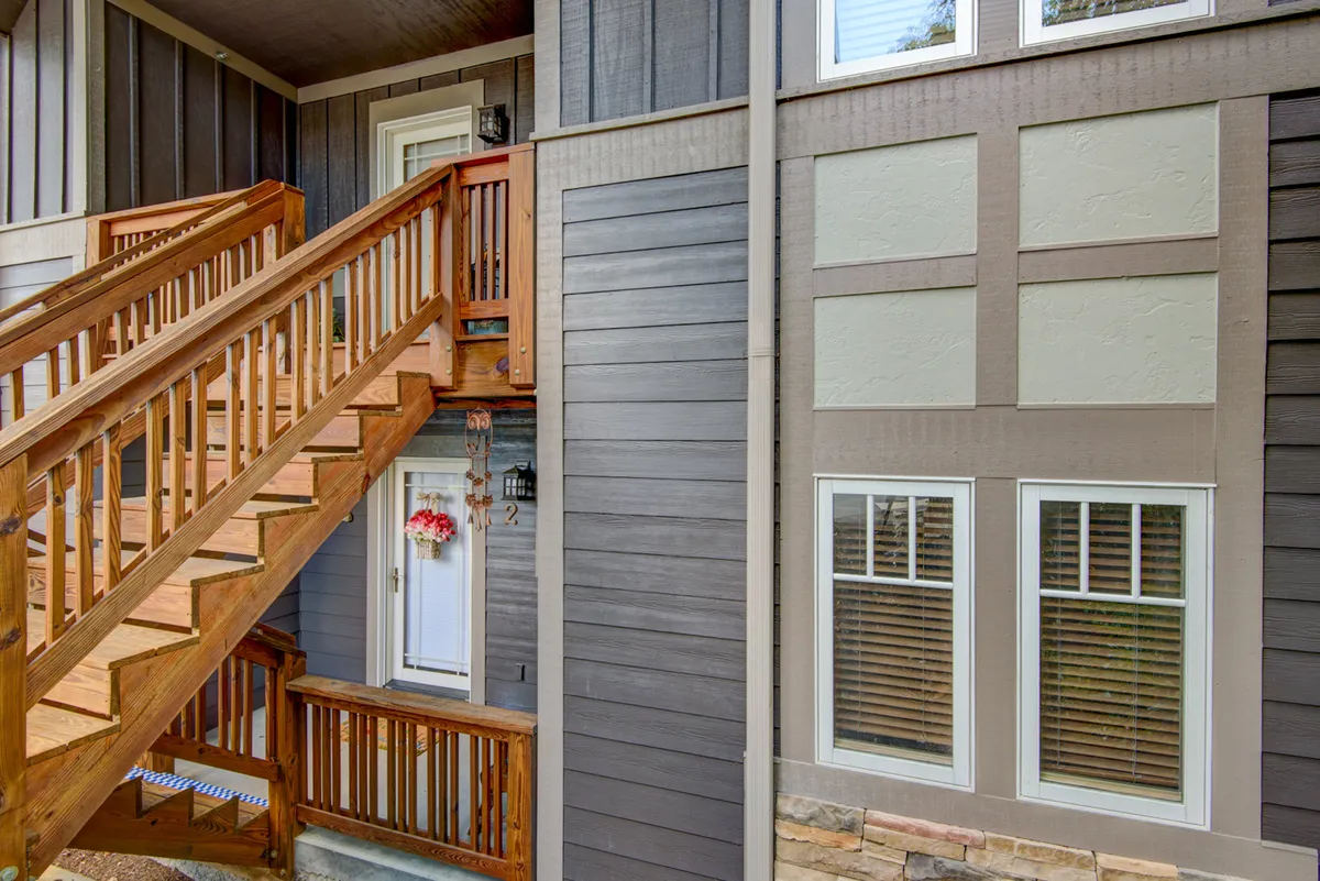 The front entry of the condo, featuring a wooden staircase, the main entrance door, and a welcoming decorative wreath. The pleasant outdoor space offers a sense of arrival and the potential for relaxed outdoor gatherings.